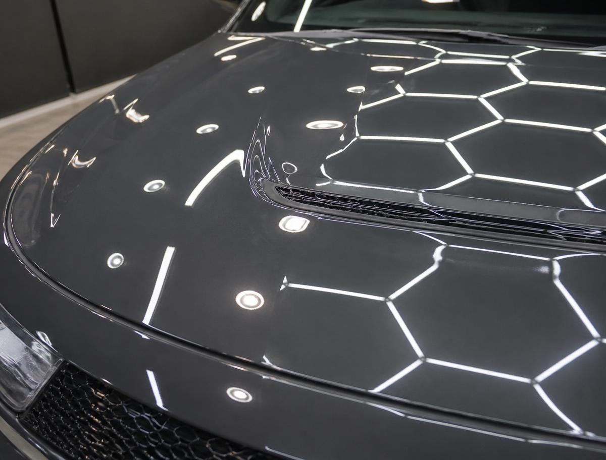 Mirror-gloss dark grey car hood reflecting studio lights after ceramic coating